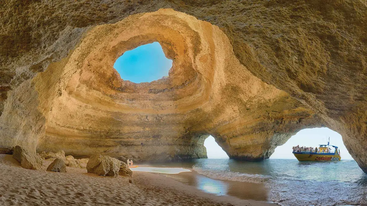 Jet-powered tour boat passing the layered sea cliffs at Benagil on a Benagil caves and dolphin watching trip, one of the classic things to do in Albufeira, Algarve